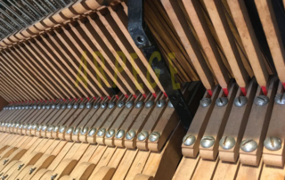 Piano Bechstein V : les prolonges ou cravates, sur des bascules qui permettent le réglage, font la liaison du clavier et de la mécanique.