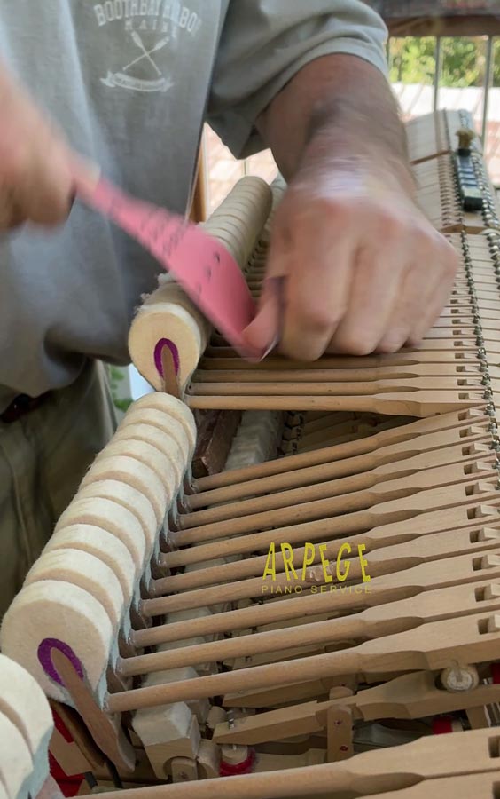 Ponçage en bande des têtes de marteaux en vue de diminuer les empruntes de cordes pour un meilleur contact avec les choeurs de cordes, dont résulte un son plus pur.