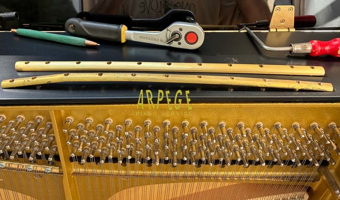 Remplacement par une barre neuve, de la barre de pression d'origine de ce piano Schimmel 119 Tradition, déformée suite à la casse de plusieurs vis.